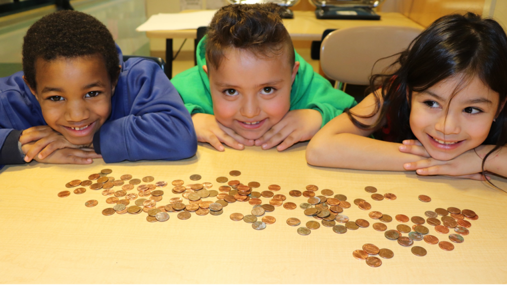 penny wars students smiling with pennies in front of them